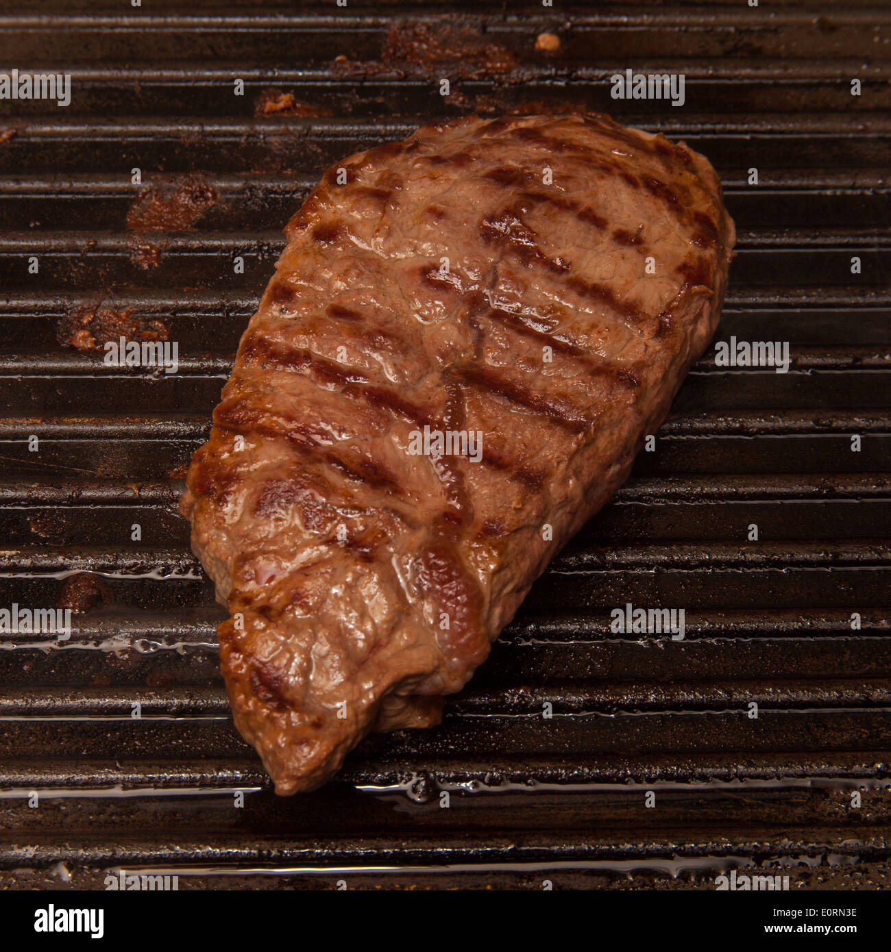 Horse meat steak cooking on a griddle. Stock Photo