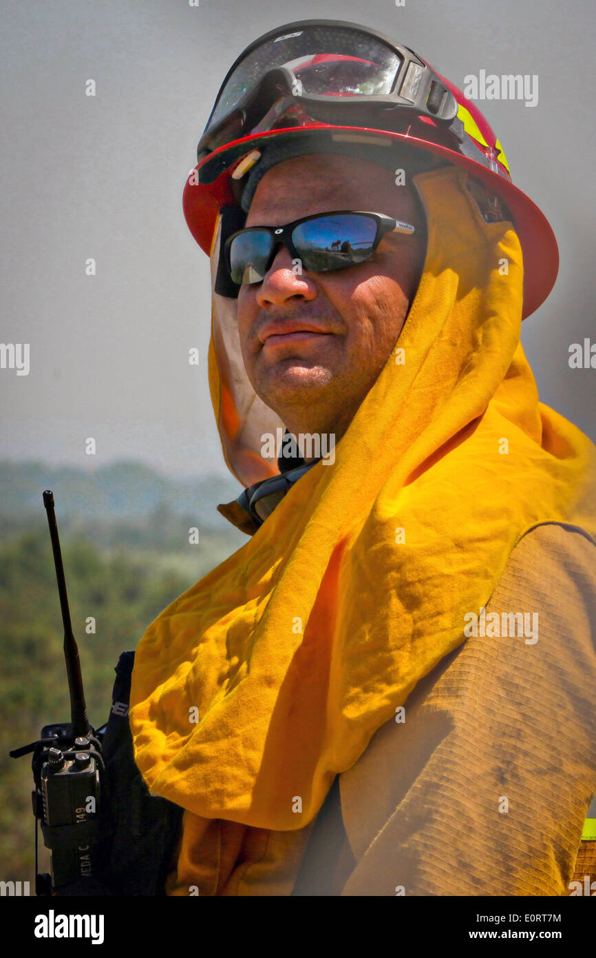 A civilian firefighter watches the Las Pulgas wildfire as it burns through parched land in the foothills around the Marine Corps Air Station May 16, 2014 in Camp Pendleton, California.  The Las Pulgas Wildfire on Camp Pendleton has burned more than 15,000 acres and is the largest fire in San Diego County history. Stock Photo