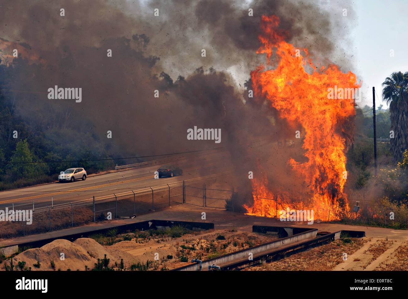 The Las Pulgas wildfire burns along a roadway in the foothills around the Marine Corps Air Station May 16, 2014 in Camp Pendleton, California.  The Las Pulgas Wildfire on Camp Pendleton has burned more than 15,000 acres and is the largest fire in San Diego County history. Stock Photo