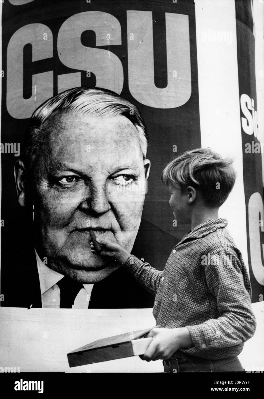Boy holding cigar up to Ludwig Erhard poster Stock Photo