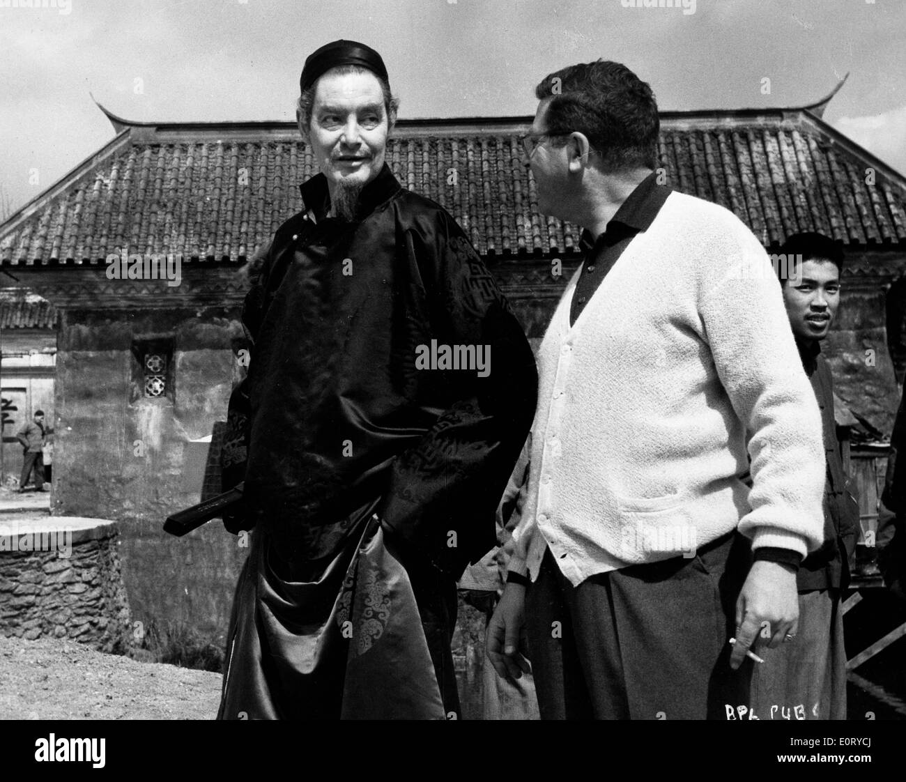 ROBERT DONAT, left, dressed in character as the mandarin Yang Cheng on the movie set of 'The Inn of the Sixth Happiness'. Stock Photo