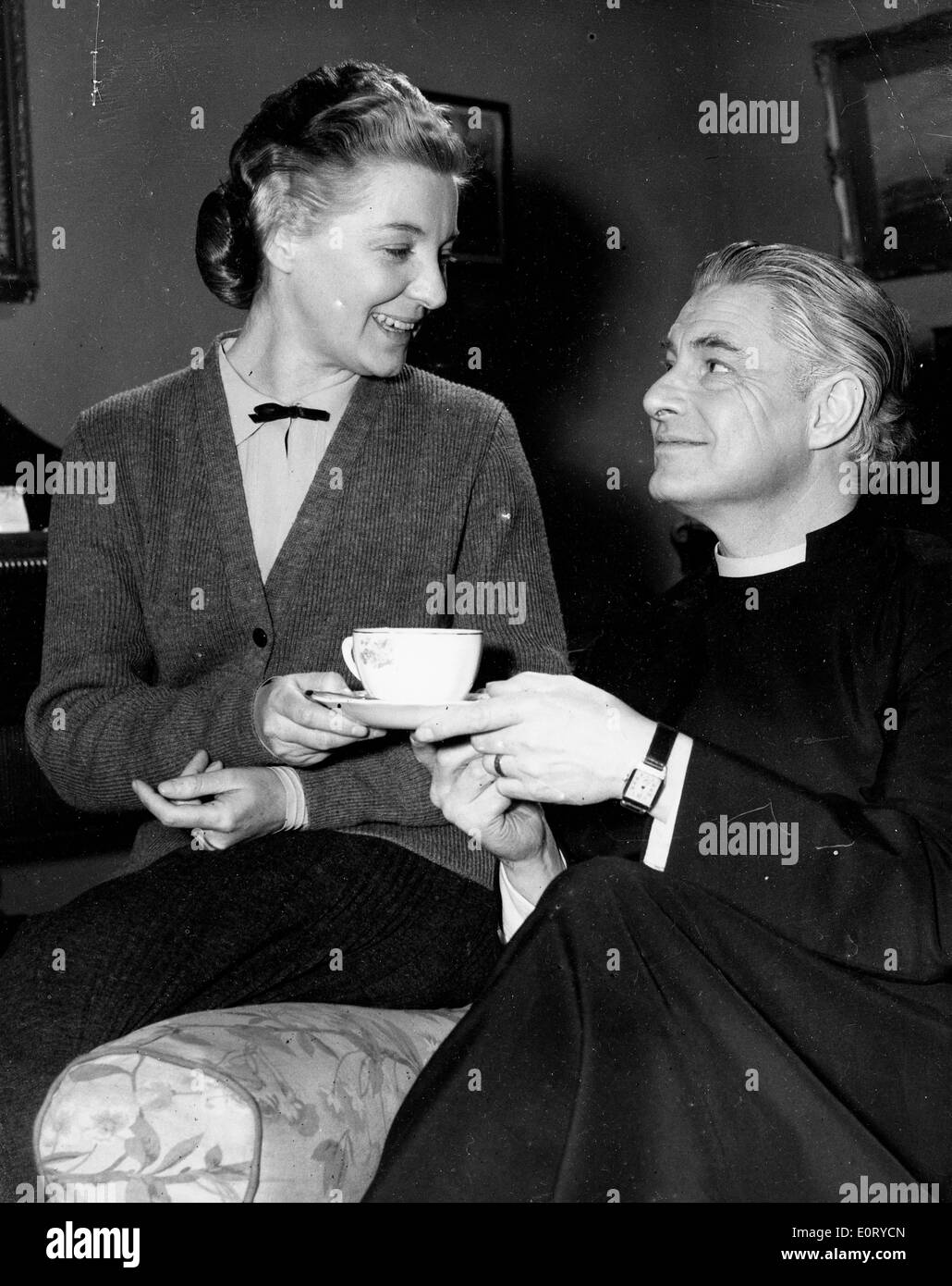 ROBERT DONAT, dressed as the Rev. William Thorne in the 1954 film 'Lease of Life', shares a cup of tea with cast member on set. Stock Photo