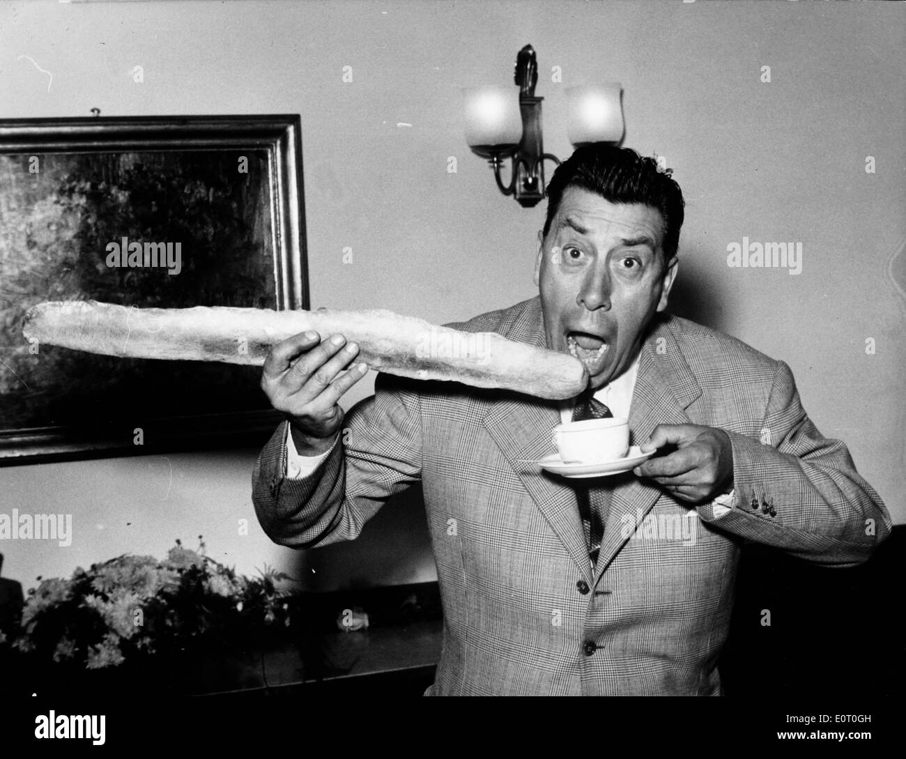 Comic actor Fernandel eating a loaf of French bread Stock Photo