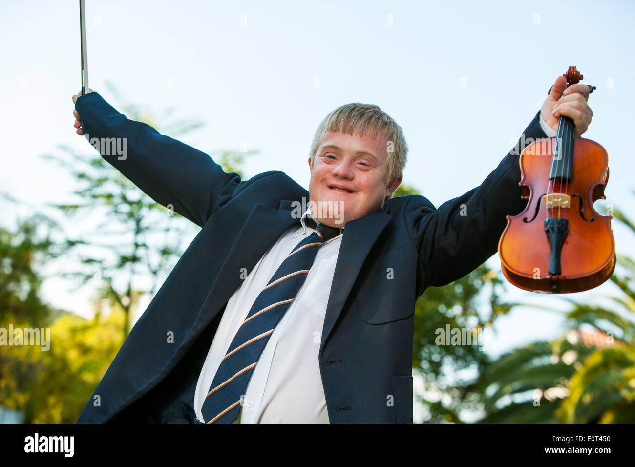 Happy handicapped violinist raising arms outdoors. Stock Photo