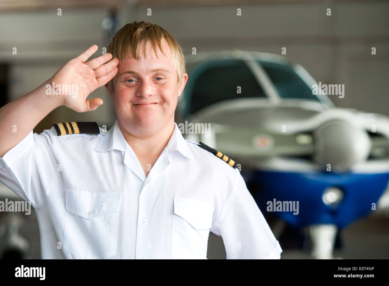 Portrait of young pilot with down syndrome in hangar. Stock Photo