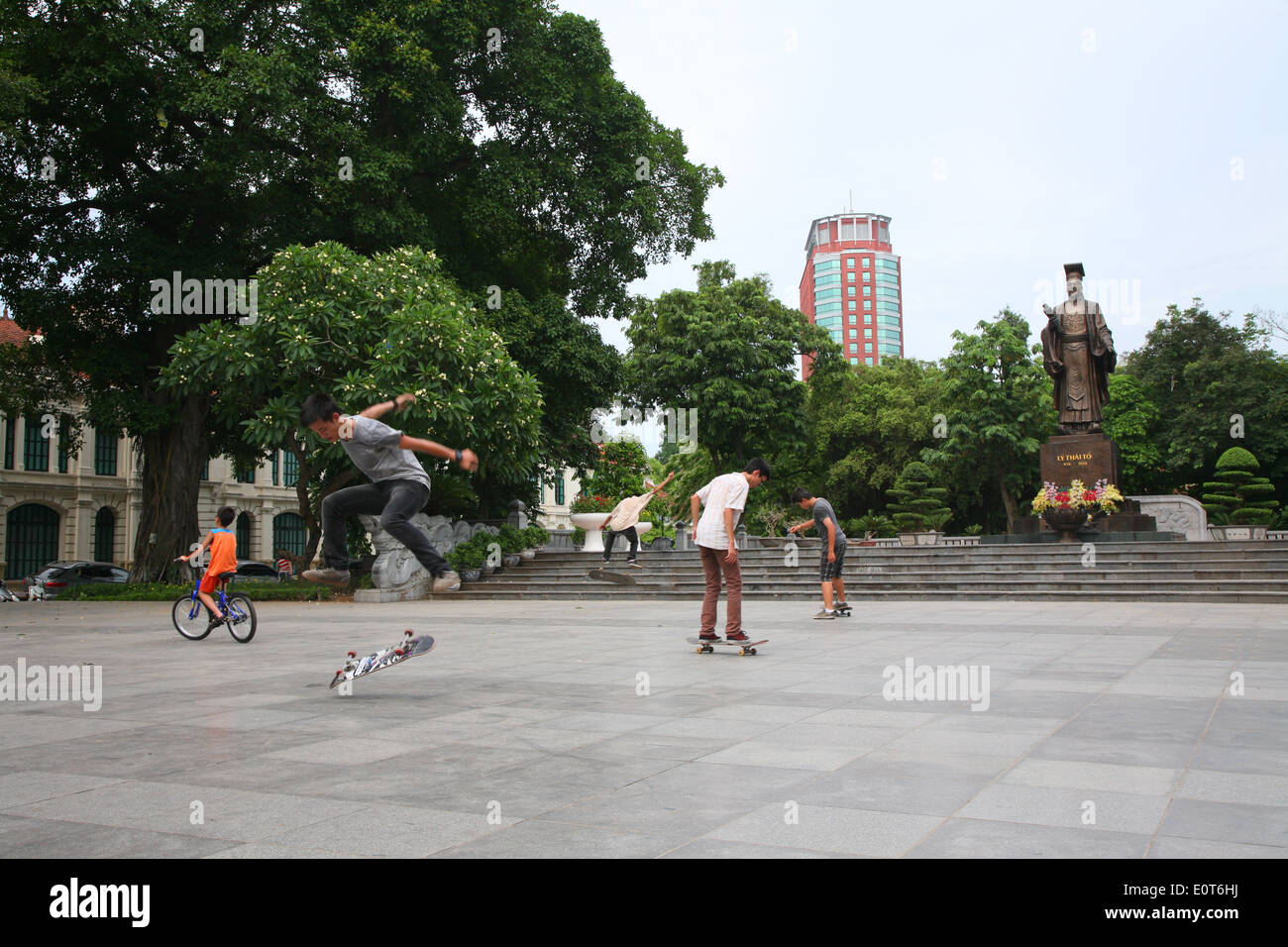 Local teenagers practice their skateboard tricks below the Statue of Emperor Ly Thai To in central Hanoi. Stock Photo