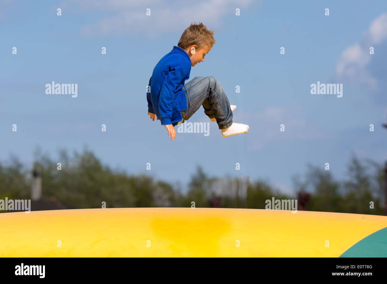 Boy jumping up and down on bouncy pad. Trademarks have been removed. Stock Photo