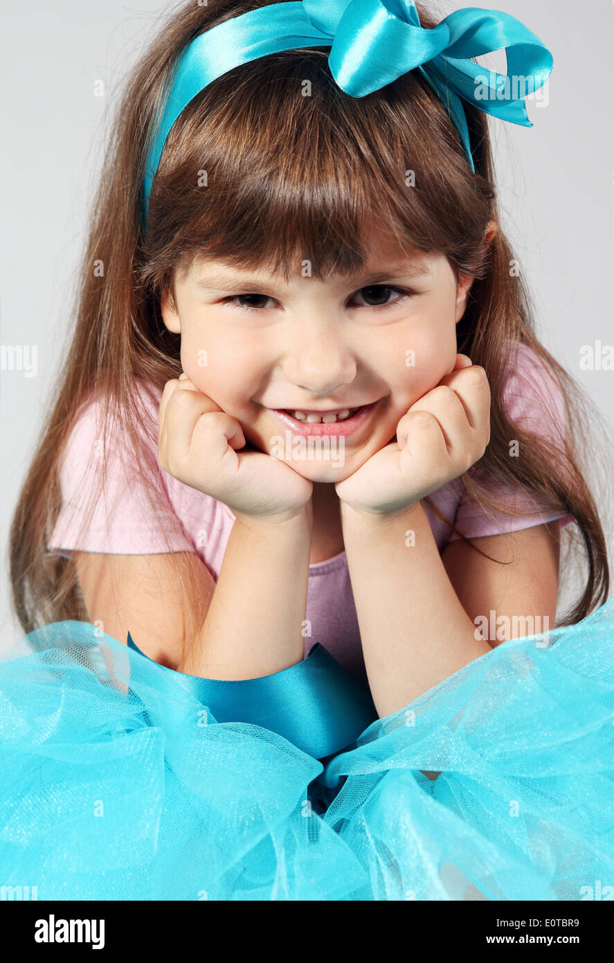 Little Smiling Girl Sitting Hands Proping Up Chin Stock Photo