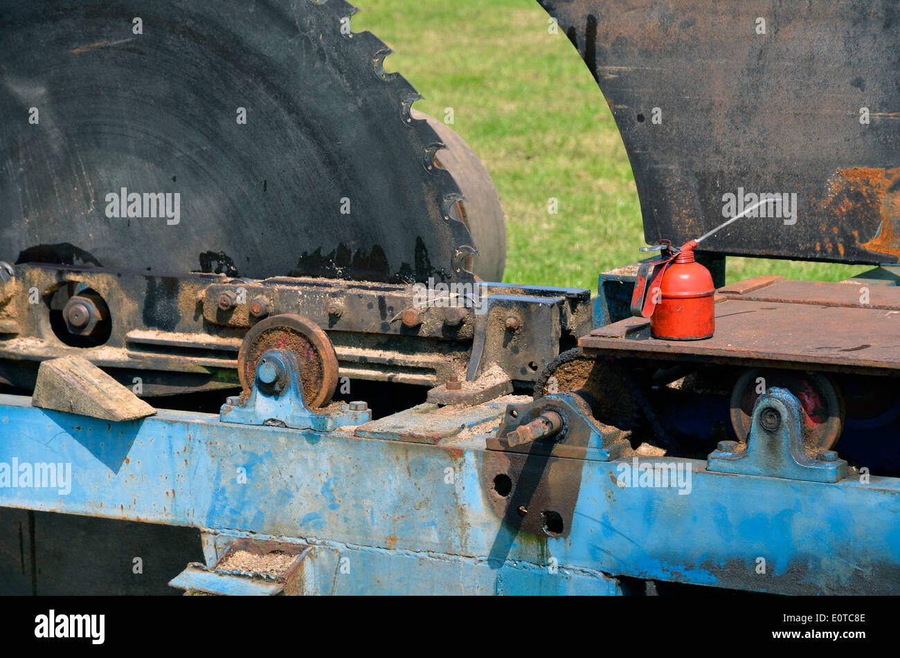 An old portable saw bench with a large circular saw blade and a red can of lubricating oil at a country fair. Stock Photo