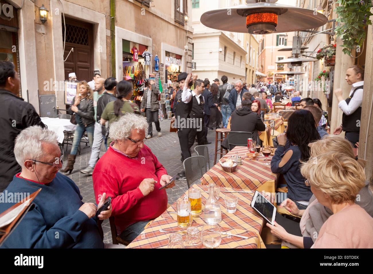 People sitting in a street cafe in Trastevere, Rome, using their mobile ...