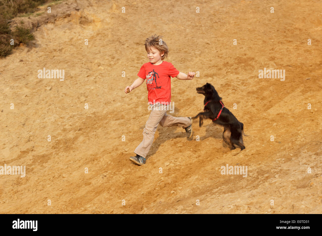 young boy running with his dog jumping beside him Stock Photo