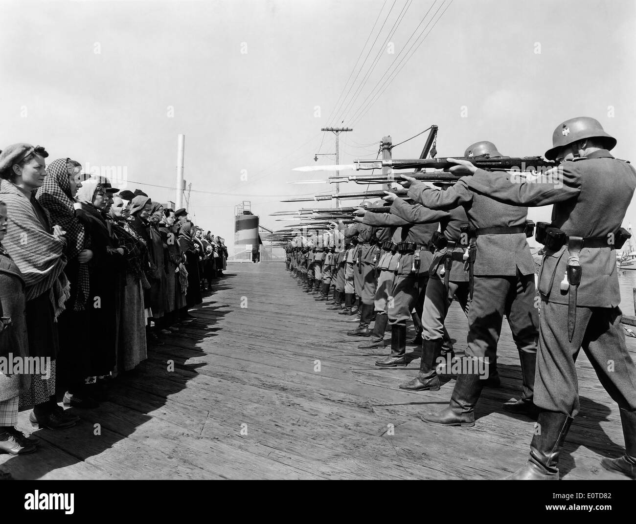 Row of German Soldiers with Rifles and Bayonets aimed at Norwegian Prisoners, on-set of the Film, 'Edge of Darkness', 1943 Stock Photo