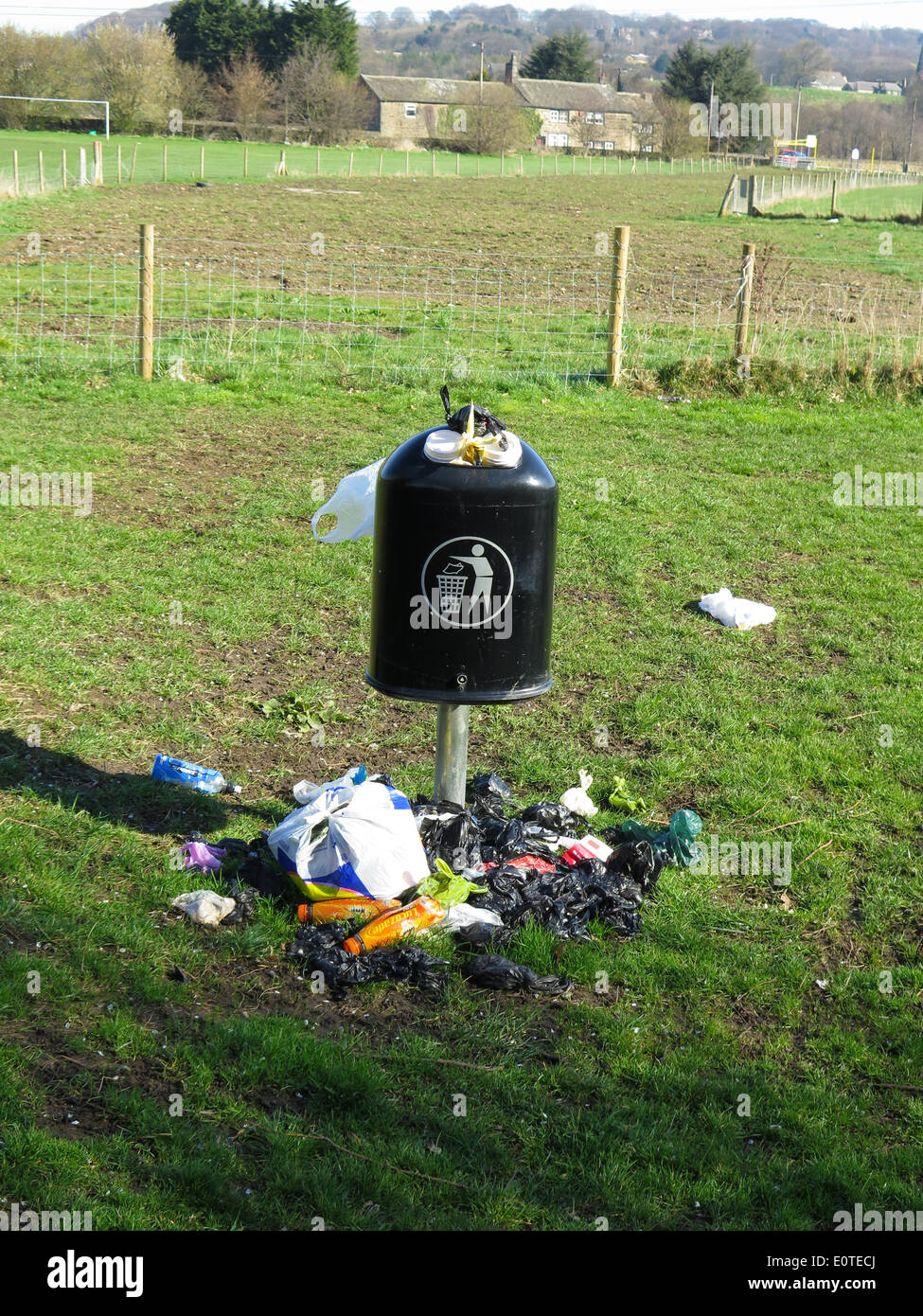 Unemptied litter bin spewing rubbish on to the grass Stock Photo Alamy
