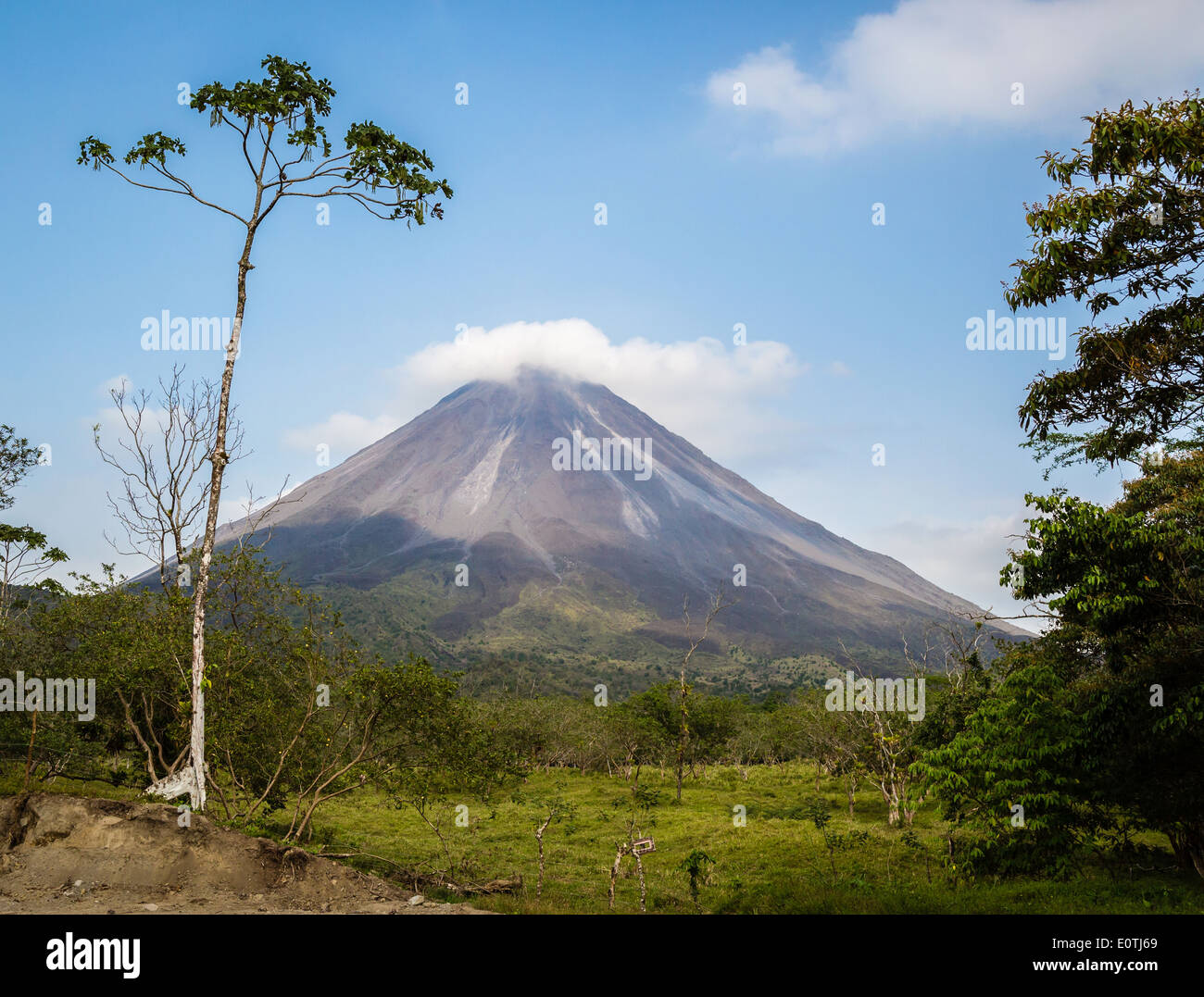Quietly active Arenal volcano with a light capping of pyrocumulus cloud in evening light - La Fortuna Costa Rica Stock Photo