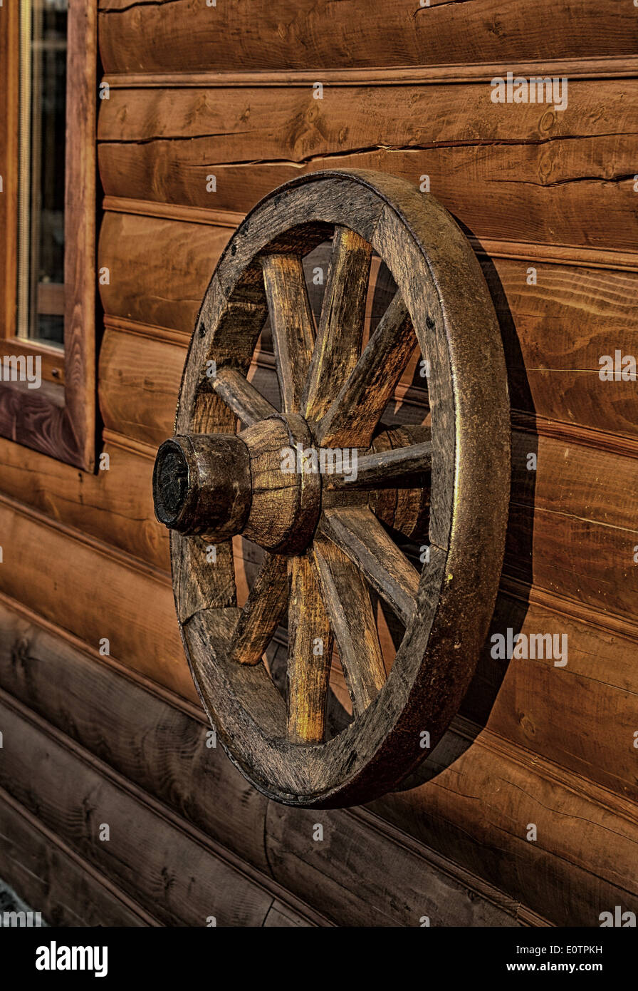 The old wooden wheel from a cart hangs on a wall from natural logs Stock  Photo - Alamy