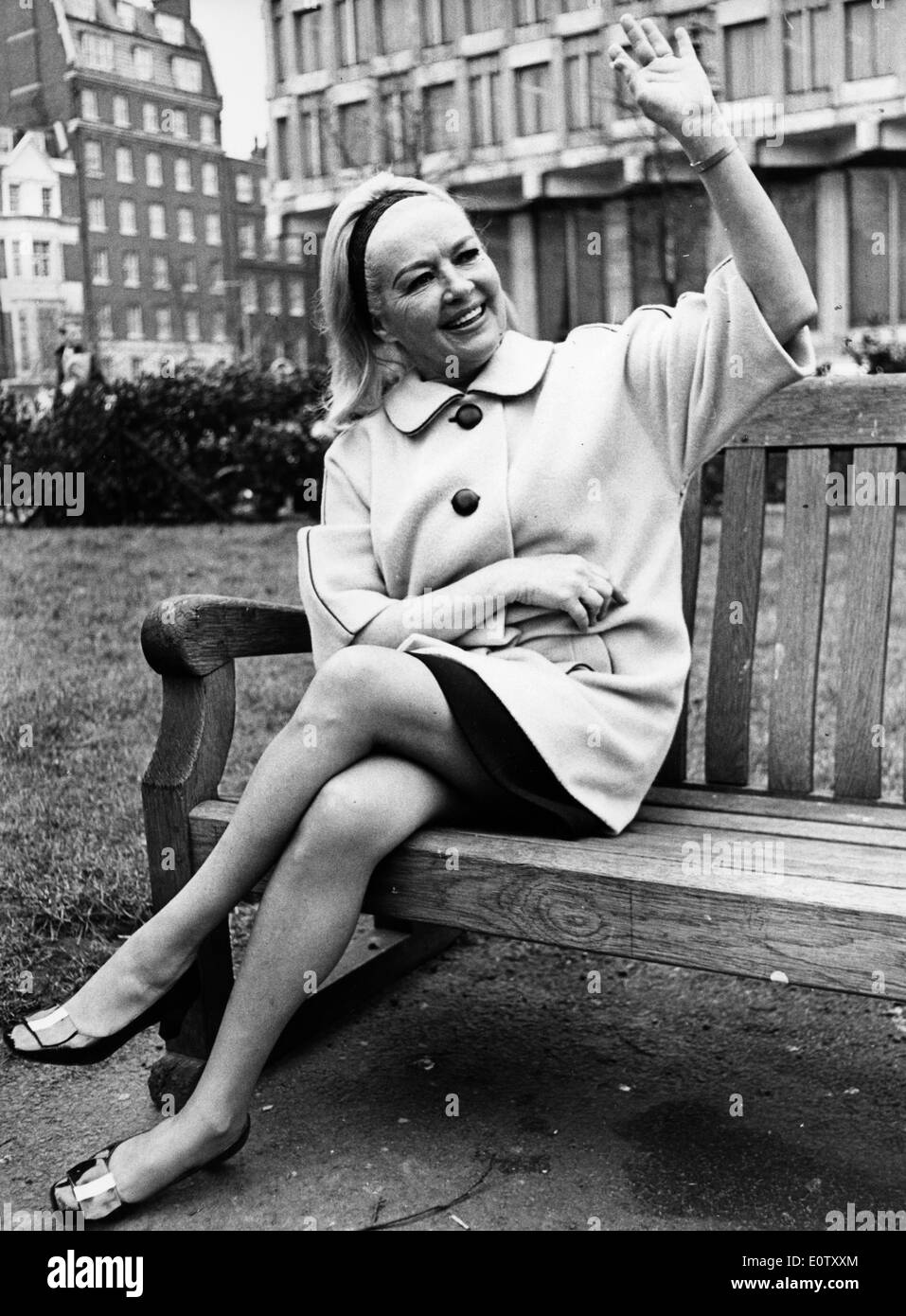 Actress Betty Grable waving from a park bench Stock Photo