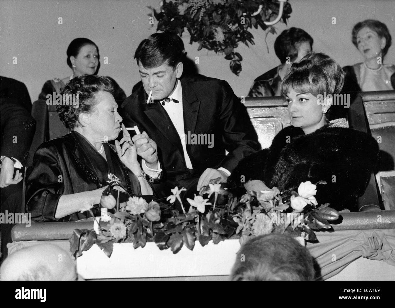 Jean Marais lighting a woman's cigarette at an event Stock Photo