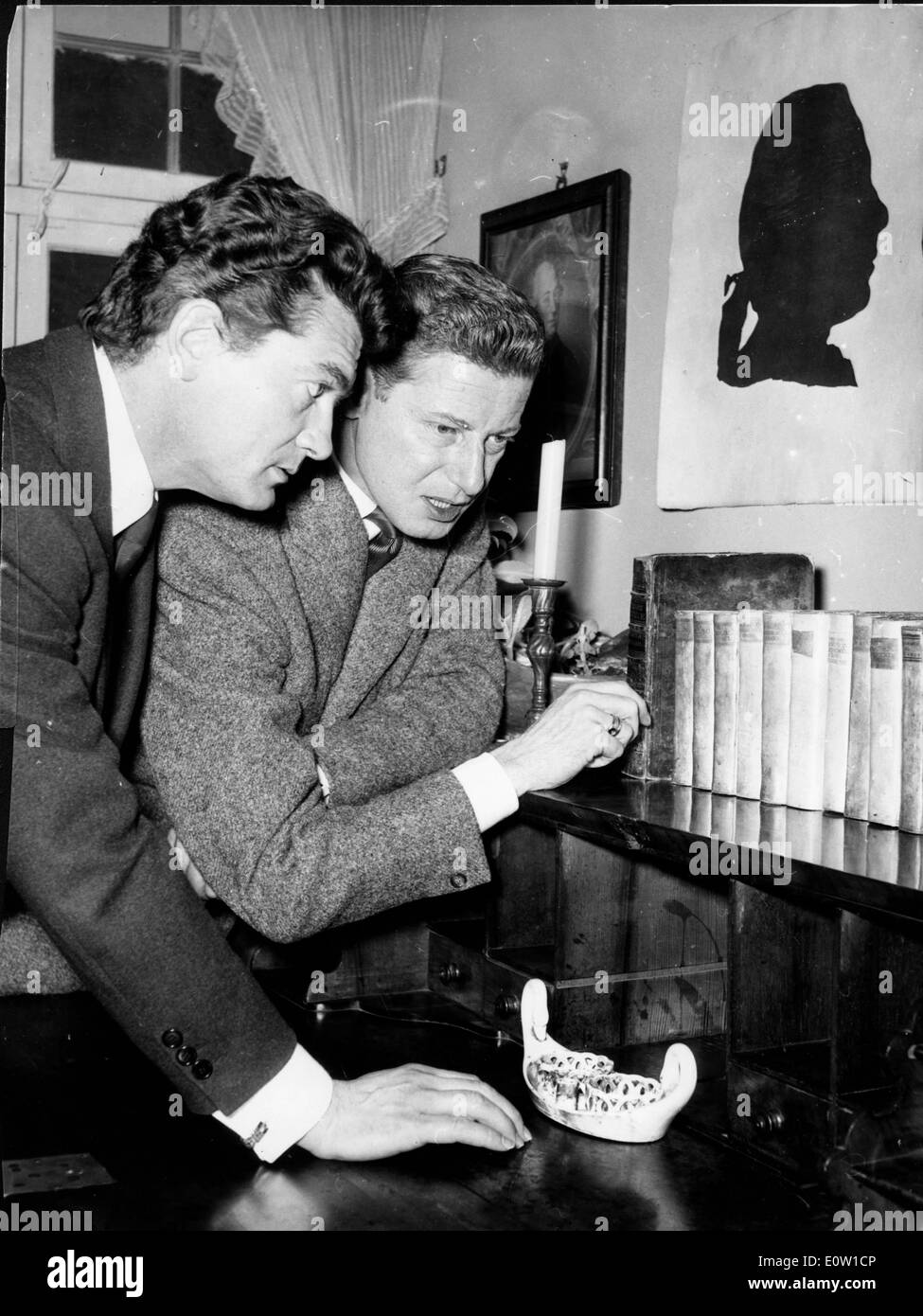 Jean Marais and a friend selecting a book from the shelf Stock Photo