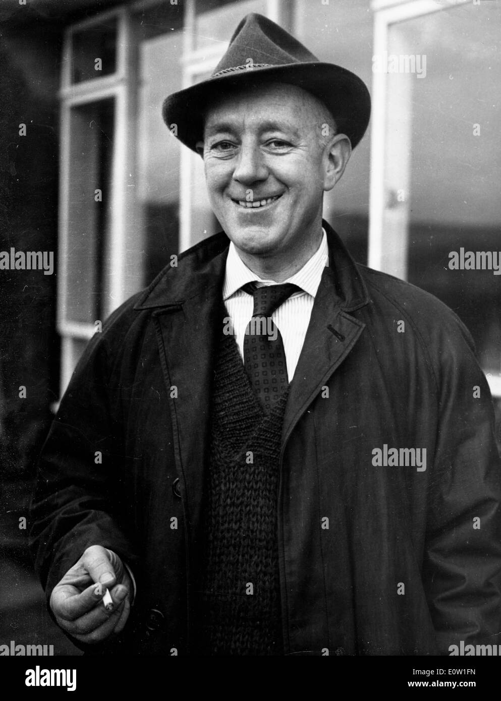 Actor Alec Guinness having a cigarette outside his house Stock Photo