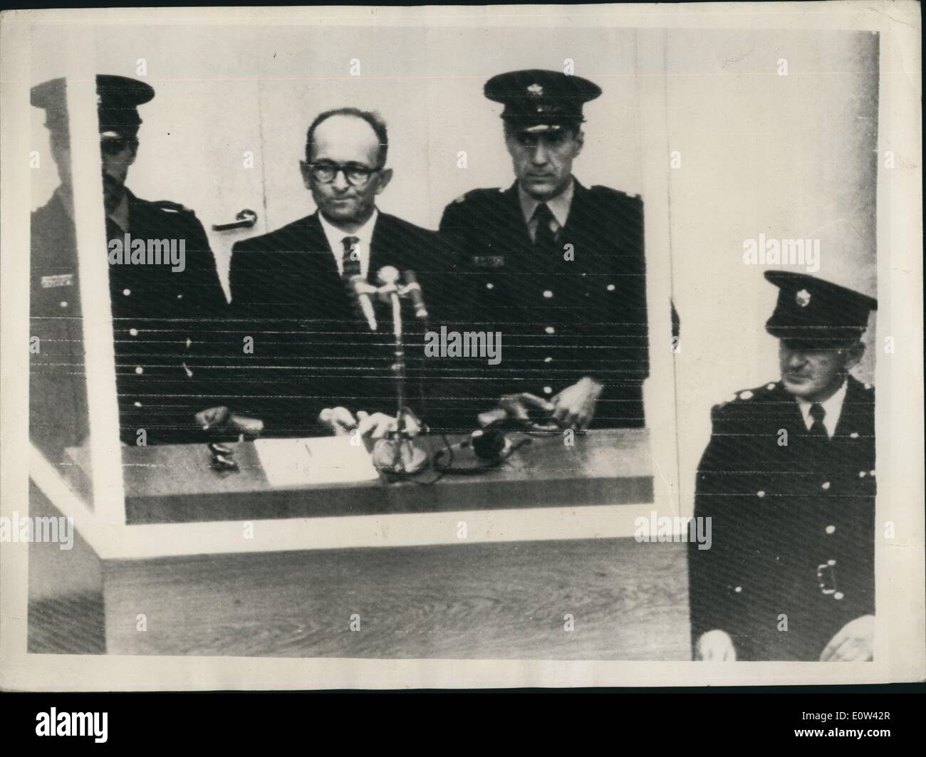 Apr. 04, 1961 - Opening of the Adolf Eichmann trial in Jerusalem. Charged with Mass Murder of the Jews: The trial opened this morning in Jerusalem of Adolf Eichmann former Nazi S.S. Colonel on charges of the mann murder of millions of Jews in concentration camps during the war. Photo Shows Well guarded with a policeman on either side of him Adolf Eichmann seen in his special bullet proof dock at the opening of his trial in Jerusalem this morning. Stock Photo