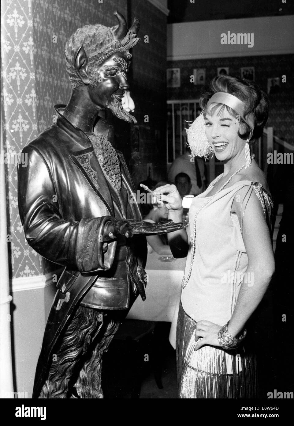 Actress Dawn Addams using the Devil statue as an ashtray Stock Photo