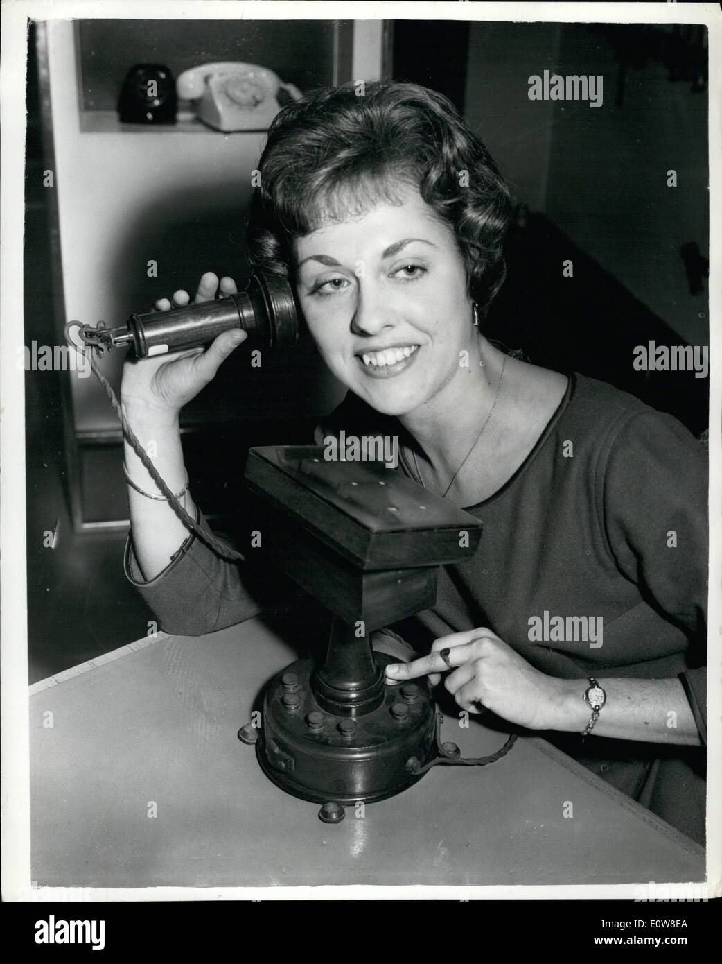 Nov. 11, 1961 - Historical telephone Equipment on show in London. A permanent exhibition of historical telephone equipment was opened this morning at Fleet Building, Farrington Street. The exhibition illustrates the progress in telephonic equipment through the ages. Keystone Photo Shows: Audrie Cooper of Lewisham with the oldest telephone in the exhibition. It the French ADER telephone with carbon pencil transmitter. The wooden diaphragm has been replaced by a platic one to show the carbon pencil. Stock Photo