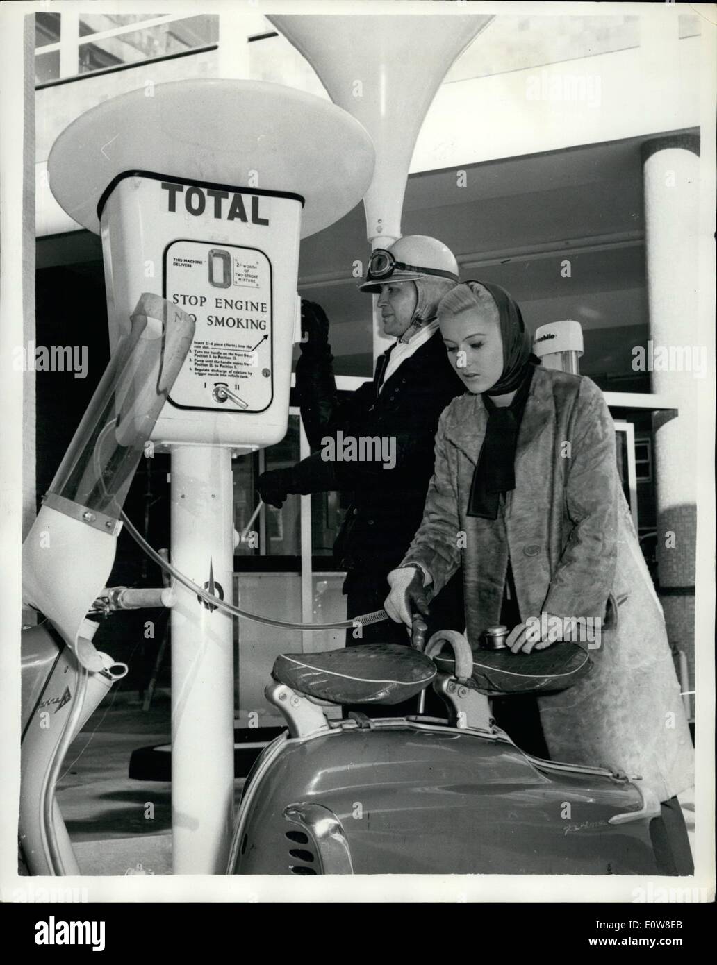 Nov. 11, 1961 - Self-Service Petrol Pump: For the first time in London at the new Total service station near Southwark Bridge, a special self-sevice pump provides ''help-yourself'' petroil mixture for mopeds and scooters. Users insert a two-shilling piece, turn a handle, thereby pumping the mixed fuel into a container on the dispenser. Three pints are obtained for 2s. Photo shows One of the first customers to use the new pump today, John Ebbrell, of Muswell Hill, inserts his money, while model Jenny Howard, of Kingston, puts the pump's nozzele in the tank Stock Photo