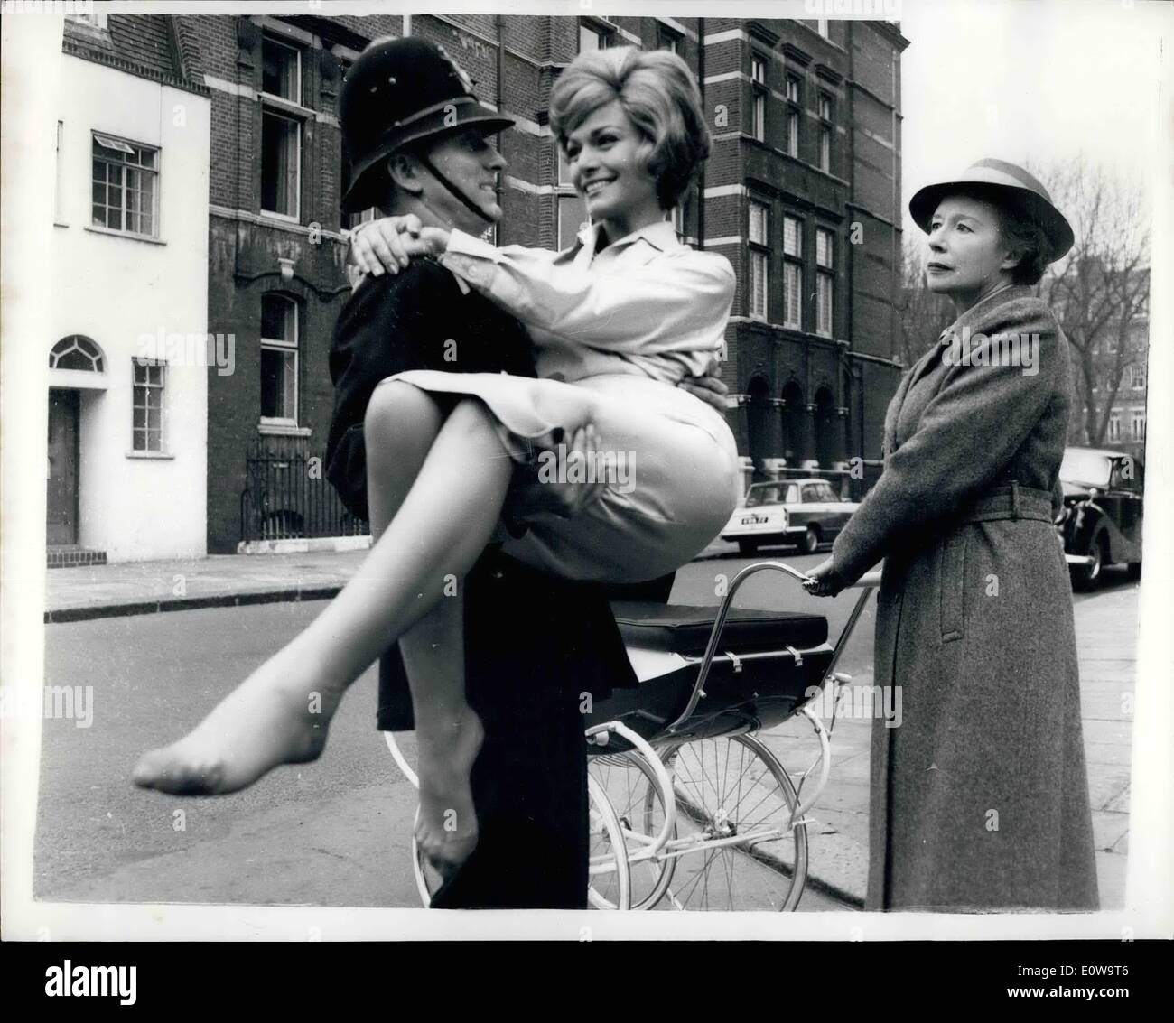Apr. 04, 1962 - Put that baby down: Can it be spring fever when a London bobby is seen gaily carrying a pretty girl in SW 1? It's enough to make a passing nannie give him a look. a put-that-baby-down-at-once look. But don't blame spring fever. For the beautiful baby in the policeman's arams is German actress Margit Saad. And it's a seene shot in Clabon-mews, Cadogan-square, Chelsea for the film Playback. Stock Photo