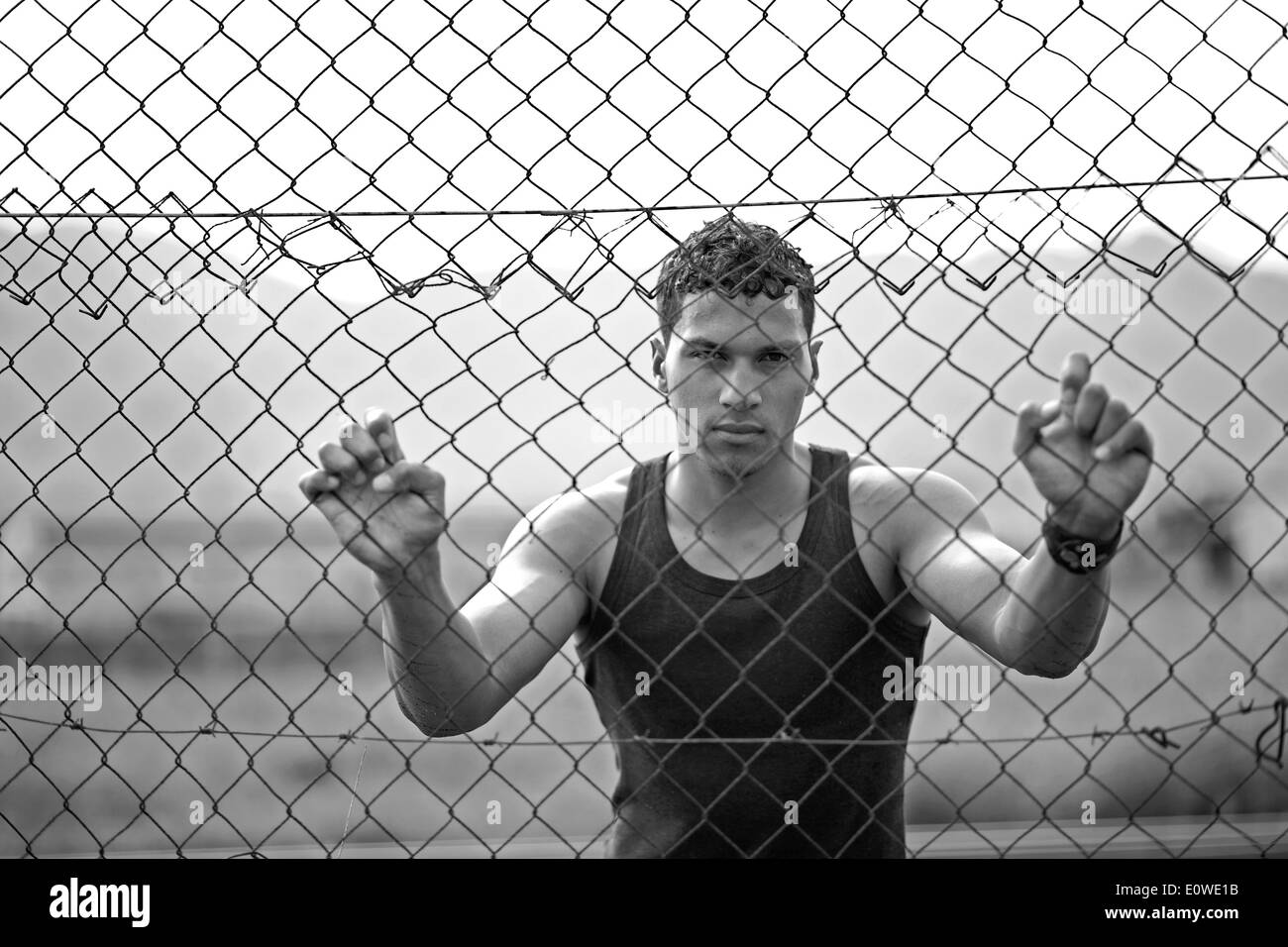 Young man holding onto a fence Stock Photo Alamy