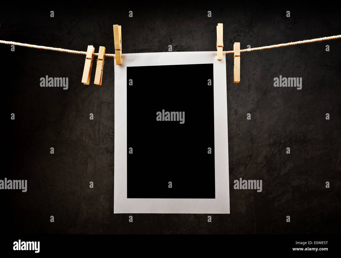 Photography paper attached to rope with clothes pins with copy space for your image over grunge texture. Stock Photo
