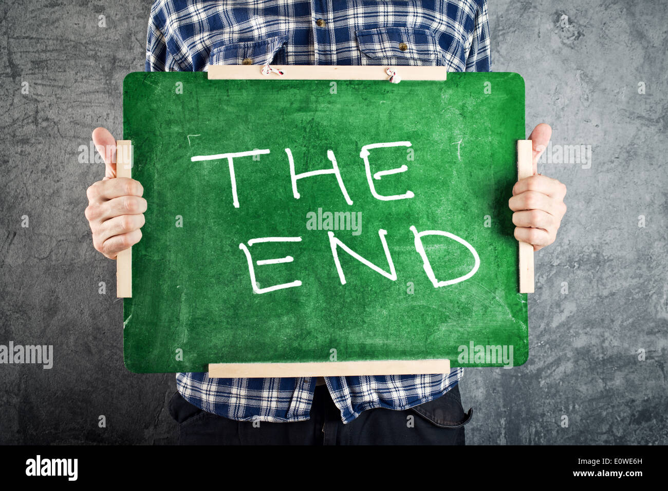 Man holding green chalkboard with THE END title. End of school year concept. Stock Photo