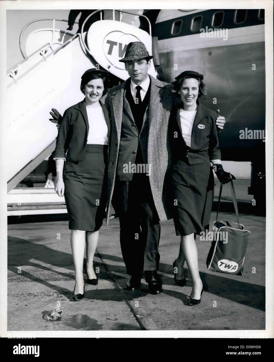 Jan. 01, 1963 - Greeted upon his arrival via TWA Jet liner from Paris, is popular French actor Yves Montand with lovely hostesses Janice Abbott on left, and Jackie Roberts. Mr. Montand is en route to Washington, D.C. to entertain at the Second Innaugural Salute for President John F. Kennedy, which takes place January 18th. Stock Photo