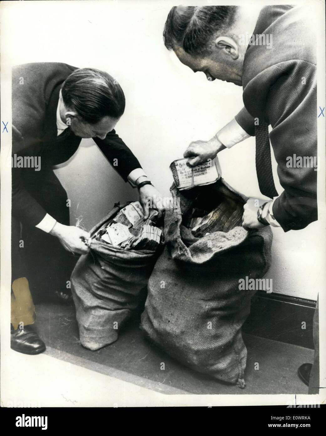 Dec. 12, 1963 - Train Robbery money found in London; Two dirty potato sacks containing about 50,000 in 5 and 1 notes stolen in the Great Train robbery last August, were found in a telephone in South London after a telephone call to Scotland Yard. Photo Shows Two detectives checking the money Scotland Yard. (left to right) Det. Chief Inspector Syd Bradbury and Det. Inap Frank Williams. Stock Photo