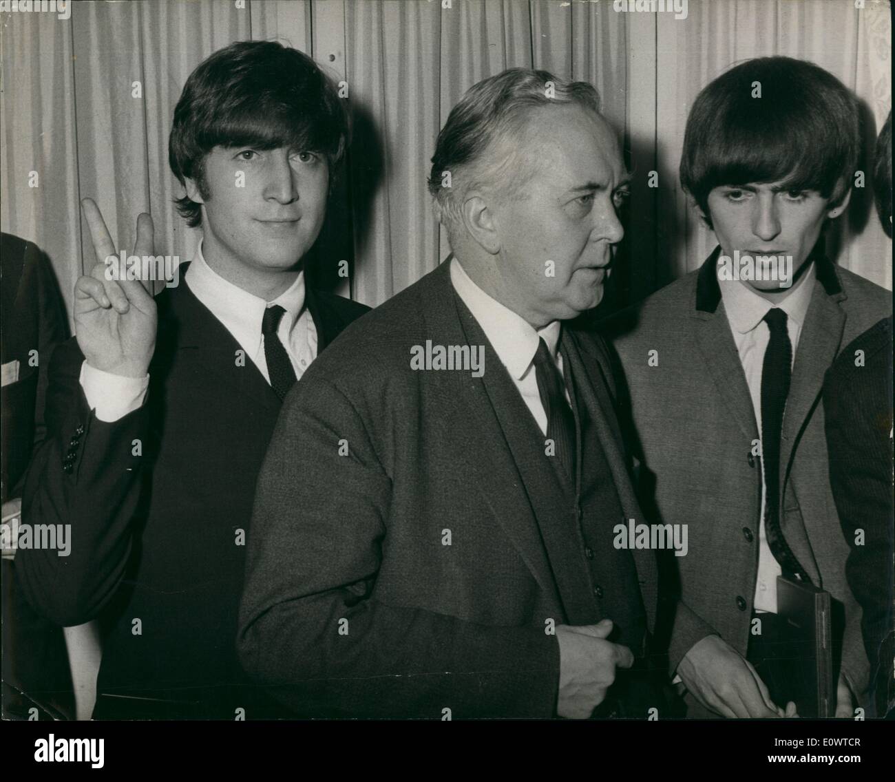 Mar. 03, 1964 - Beatles Salute Harold Wilson: Today at a luncheon at the Dorchester Hotel in London, the Variety Club of Great Britain Show Business Awards presented. Mr. Harold Wilson, leader of the opposite, was in attendance. Photo hows John Lennon of the Beatles, who received the wards for ''Show Business Personalities of 1963'' from Mr. Harold Wilson, who is incidentally Member of Parliament for their home town of Liverpool, gives the famous Winston Churchill V for Victory sign,behind Mr. Wilson's back. Stock Photo