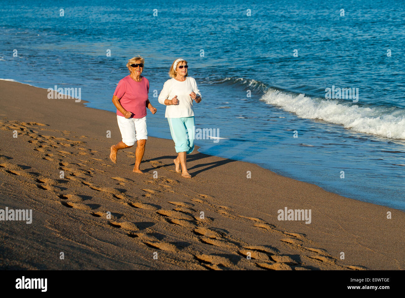 Senior women having early morning jog along sandy beach. Stock Photo