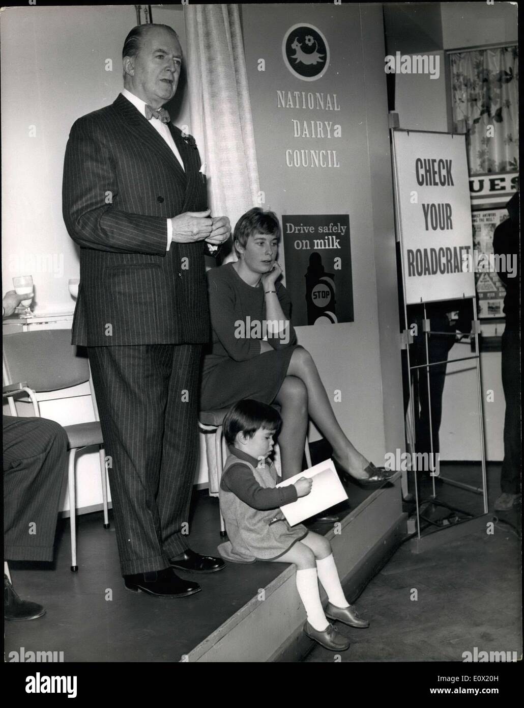 Dec. 15, 1964 - Mary Rand attends road safety exhibition opening; Popular Olympic Athlete Mary Rand this morning attended the opening of the Road Safety Exhibition at the National Dairy Center London at which Jack Warner presented her daughter two year old Alison Jane with the Tufty Club Badge. It was part of the new ''Drive Safely on Milk'' campaign. Photo Shows Jack Warner makes his opening speech with in picture Mary Rand and seated below he daughter Alison Jane. Stock Photo