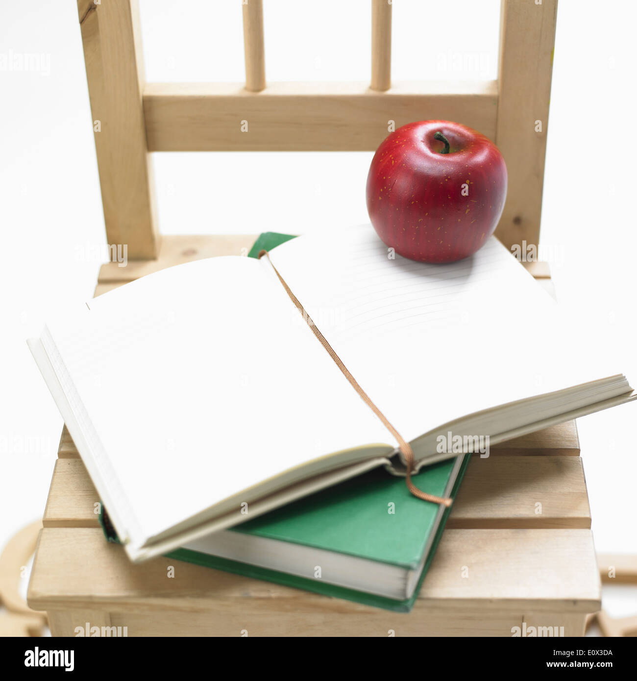 a pile of books and an apple on top of a chair Stock Photo