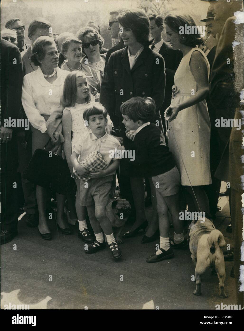 May 05, 1965 - Jackie Kennedy and her sister go to Buckingham Palace with their children: Mrs. Jacqueline Kennedy and her two children John, 5 and Caroline, 7, accompanied by her sister, Princess Radziwill, and her two children, walked from the Radziwill home in Buckingham place, through the park to Buckingham Palace today. They were invited inside to watch the ceremonial changing of the guard. Photo Shows Jackie Kennedy (dark coat) and her two children, Caroline and John (holding a loaf of bread) pictured with Princess Radziwill and her son Anthony outside the Palace today. Stock Photo
