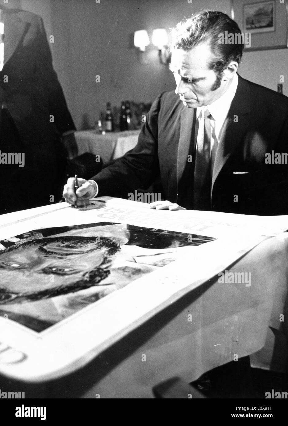 Actor Charlton Heston signing a poster of himself for 'The Agony and the Ecstasy' Stock Photo