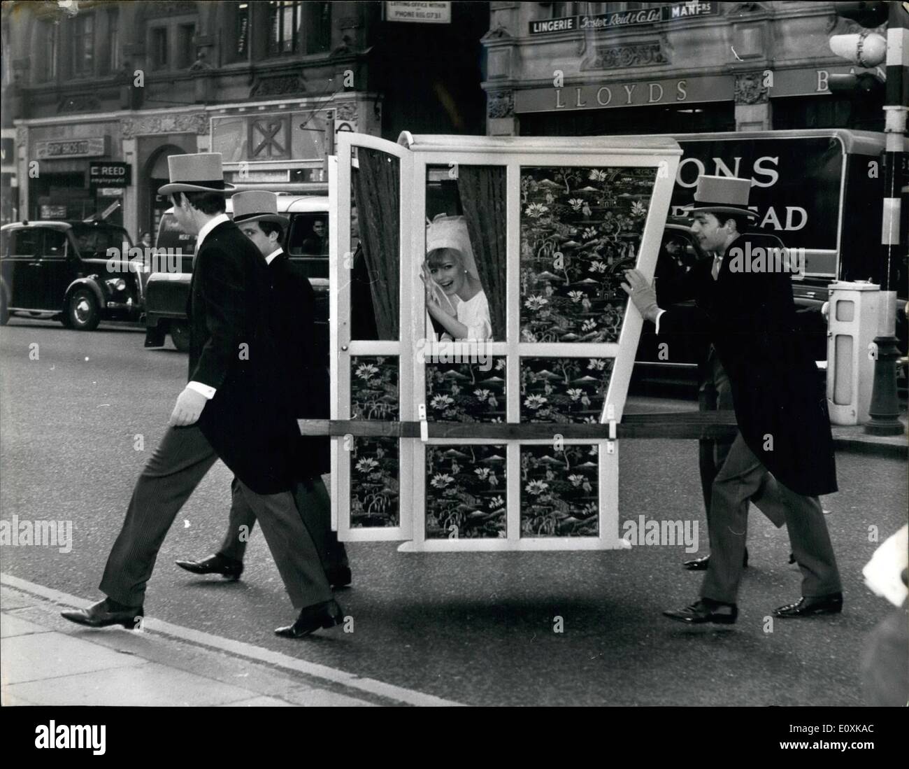 Mar. 03, 1967 - Getting to the Church - by Sedan: A bride in a four-manned Sedan chair versus a 210-horses power car, set off for St. Ann's Church in Wardour Street, from Young's Dress Hire, 178, Wardour Street, W.1. this morning - to prove that in congested towns, man power beats motor power at getting the bride to Church on time. Especially at Easter, Bridal hire specialist Louis Young thinks the return of the sedan chair could be a pretty and practical idea for brides Stock Photo