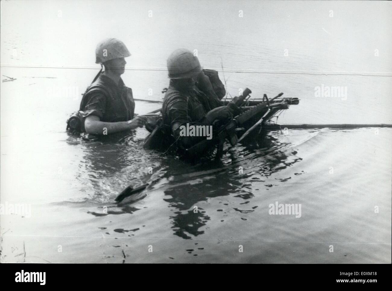 Apr. 04, 1967 - VIETNAM WAR. SHIPWRECKED. Two U.S. Marines struggle ashore in a Vietnam river after their sampen had sunk during the crossing due to too much top weight. They managed to salvage most of their equipment when the flimsy craft turned turtle. Stock Photo
