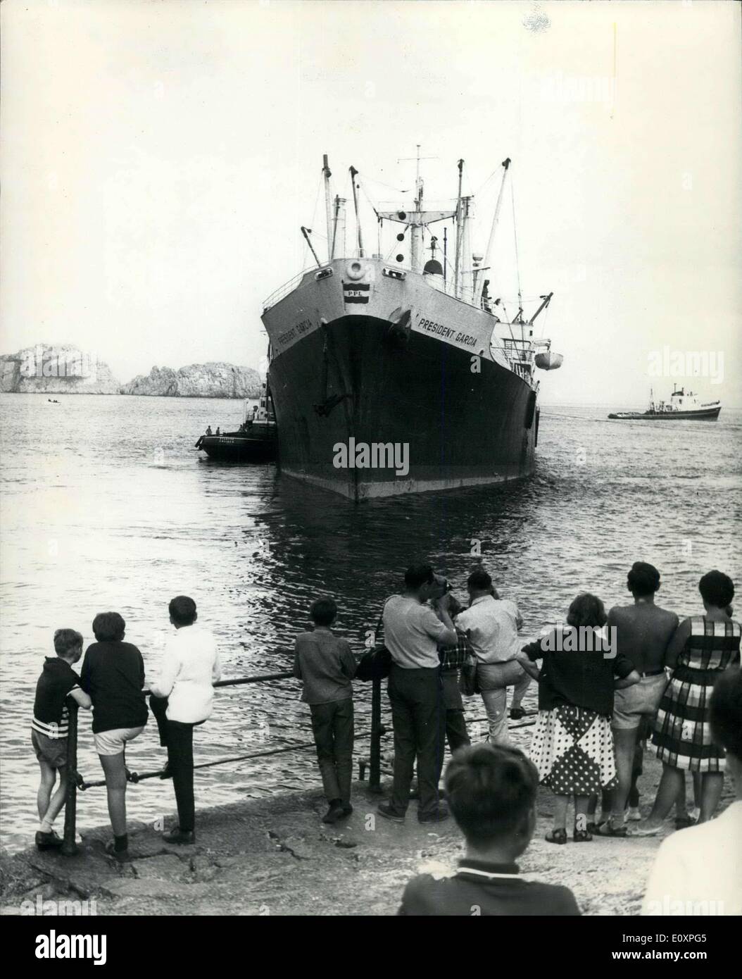Jul. 22, 1967 - Stranded Car Ship Freed In Guernsey: The Philippine cargo ship President Garcia which was aground for a week, was successfully towed off the rocks at Saint's Bay, Guernsey by three Dutch tugs on Thursday evening. The tugs, two at sea and one alongside, took an hour to slowly shift the ship. Scores of holidaymakers watched the operation and cheered the crew as the ship was pulled off. Photo shows Holidaymakers look as the ship is pulled off the rocks at Saint's Bay Guernsey. Stock Photo