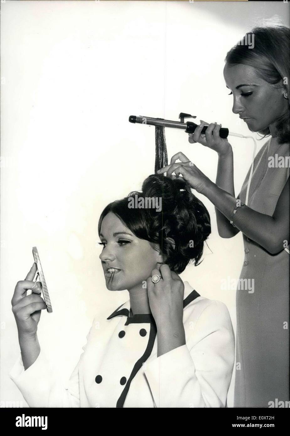 Sep. 02, 1967 - Turning her locks into a fashionable hairstyle is no ''hairy situation'' for Margo, a young photo model from Munich. Margot conjures fluffy locks and waves in the blink of an eye in the hair of her sister Gabriela with a new styling iron. The verdict for this smoothly-worn hairstyle? This 'curly locks' look is the new reigning fashion. The hair style is beautiful and silky, but unfortunately is quite vulnerable to the weather. Pass through a mist or fog and your beautiful creation will change into a mess of sad wisps Stock Photo