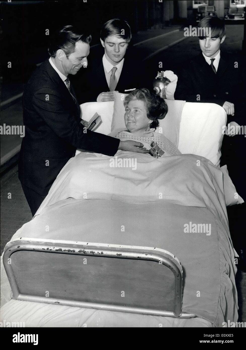 Mar. 12, 1968 - March 12, 1968 Mrs. Doris Page receives the MBE. Mrs. Doris Page, 42, is pictured in a bed in the quadrangle of Buckingham Palace today, showing her husband Kenneth, and her two sons, Brian 17, and Andrew 15, the MBE which was presented to her by Queen Elizabeth II. Mrs. Page, of Essex Street, Newbury, Berkshire, England, is a polio victim and uses an iron lung, received her award for her work as editor of the magazine Responaut for people living by breathing apparatus. Stock Photo