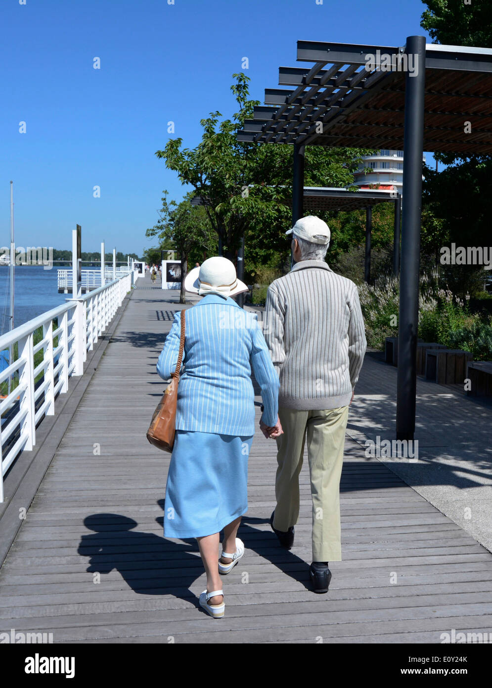 Pensioners - older couple walking - out for a stroll by the waterfront in the summer Stock Photo