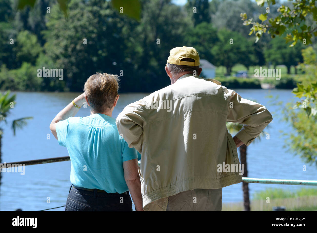 Retirees / pensioners, senior couple resting and walking by a lake in a park Stock Photo