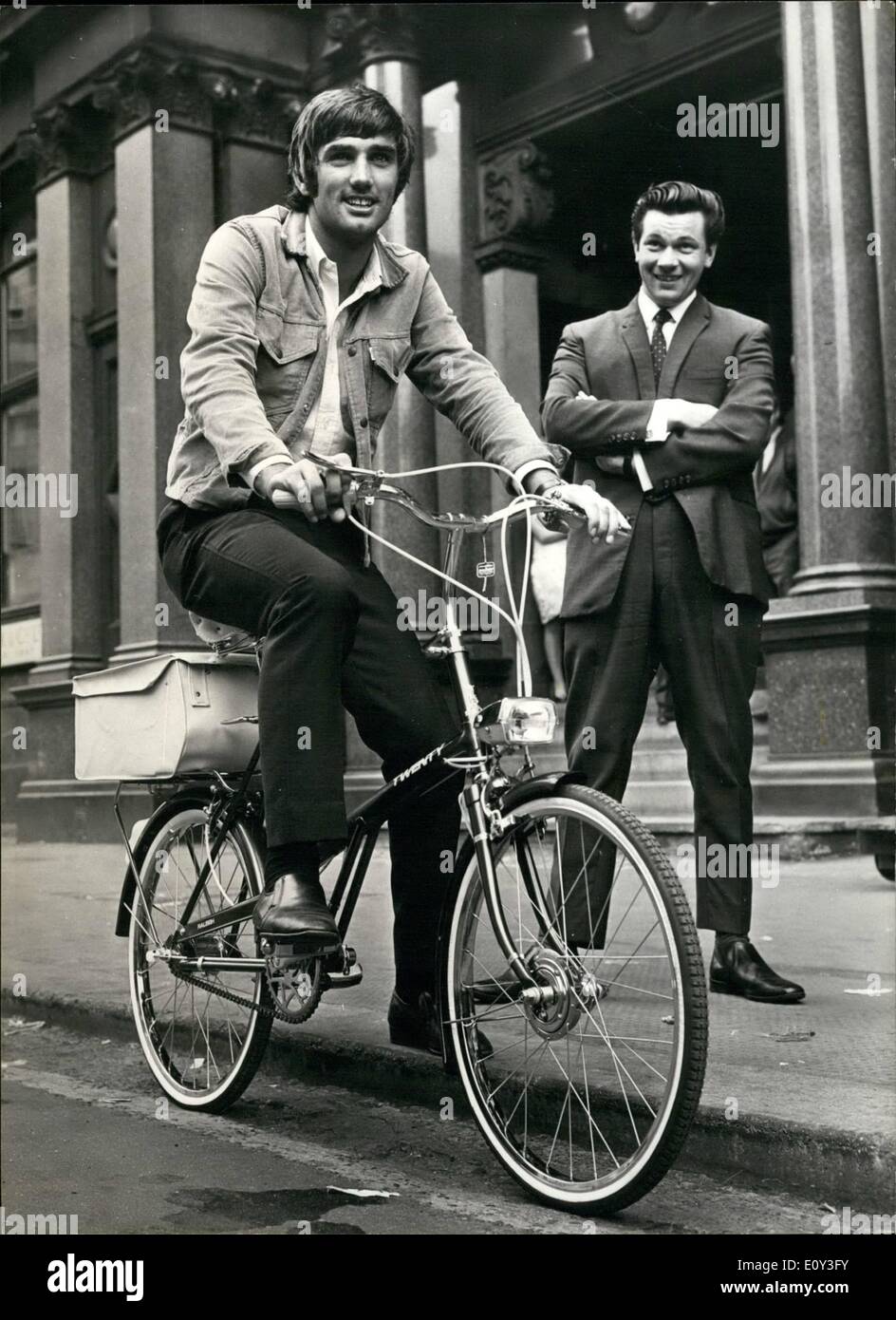 Jul. 07, 1968 - GEORGE BEST - BANNED FROM DRIVING FOR SIX MONTHS - IS PRESENTED WITH A BICYCLE. Banned from driving for six months by a Manchester Court, Manchester United's ''Footballer of the Year'' George Best, is unperturbed. He was presented with a bicycle to solve his transport problems. George received the cycle prior to a training spell at Old Trafford ground, and he rode up and down amongst the traffic to get used to the feel of his new machine. There is a large bag at the back for carrying his boots or anything else, such as fan mail Stock Photo