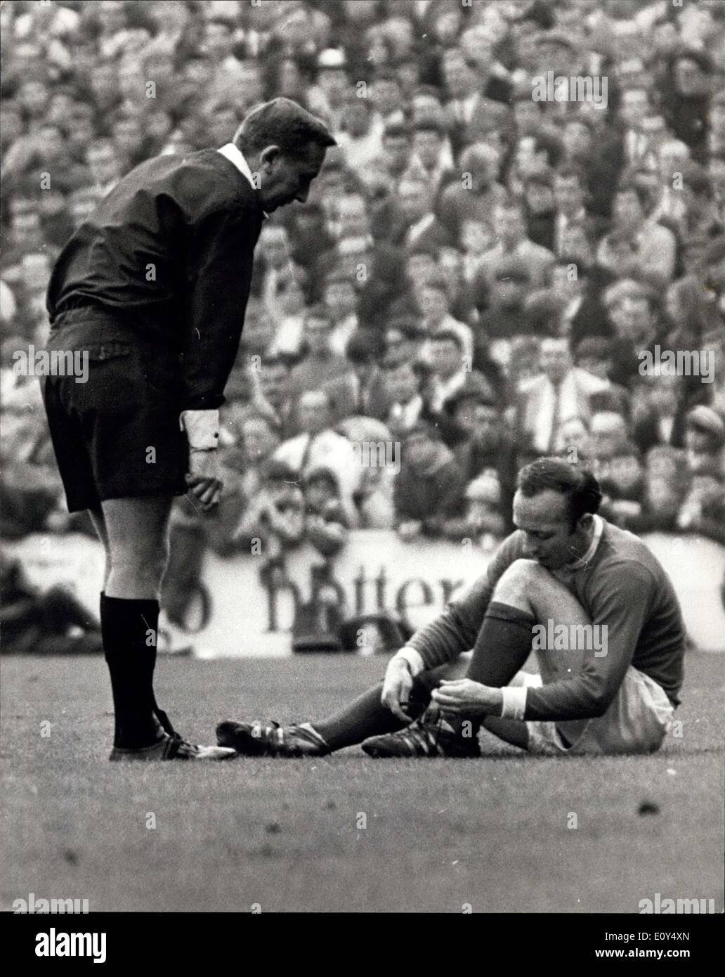 Oct. 26, 1968 - QUEENS PARK RANGERS VERSUS MANCHESTER UNITED AT LOFTUS ROAD. PHOTO SHOWS: NOBBY STILES, of Manchester United, lost his boot after taking a swipe at the ball - and is seen here as referee MR. JOHNSON tells him to get a move on while putting the boot back on. Stock Photo