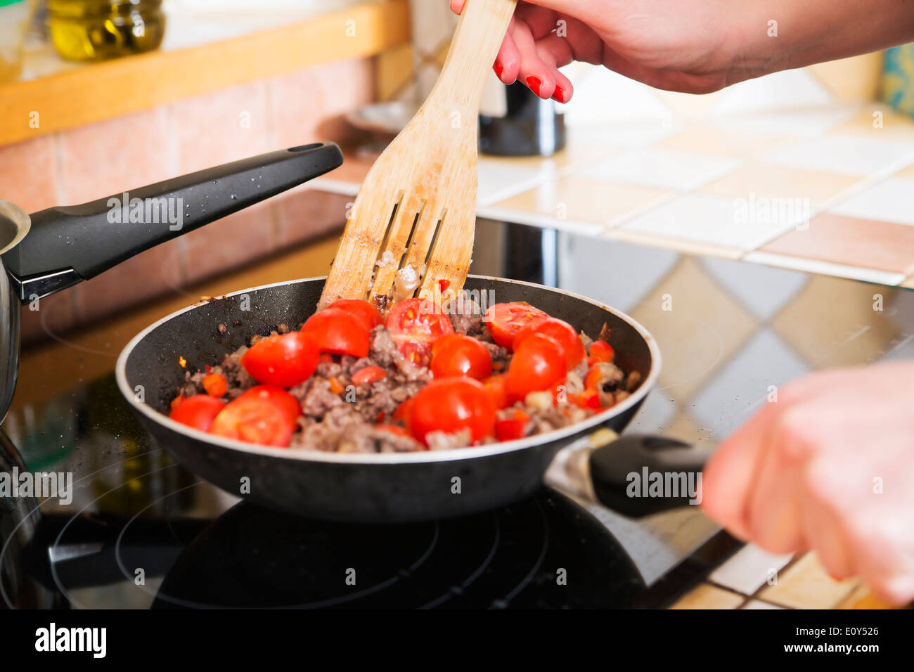 Gentle woman hands fry minced meat with tomatoes Stock Photo