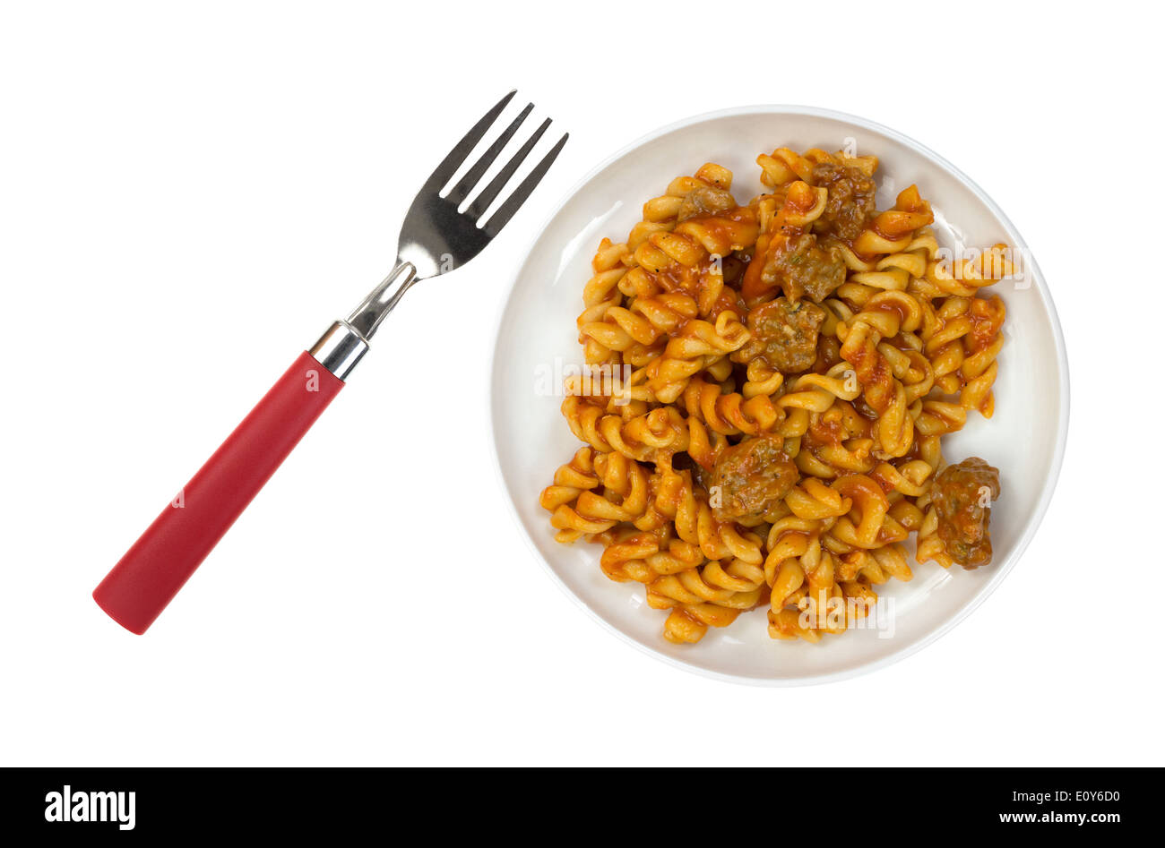 Top view of a cooked TV dinner of pasta, tomato sauce and Italian sausage on a small plate with fork to the side. Stock Photo